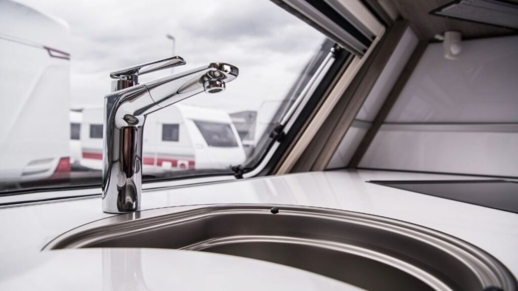 Dripping faucet inside an RV bathroom with tools laid out on the counter