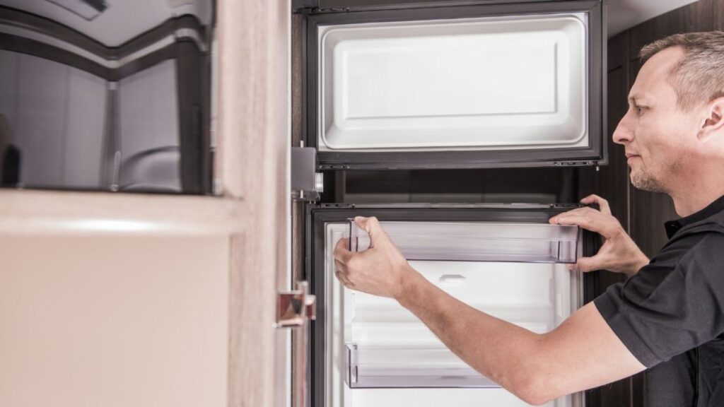  Mobile RV technician fixing an appliance outside a fifth-wheel trailer